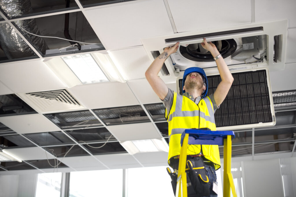 Engineer installing a ceiling air conditioning unit
